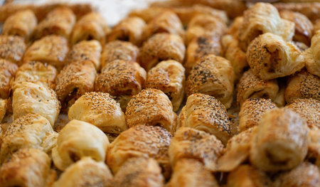 Freshly baked golden brown burekas with their flaky texture is a type of Jewish pastry. Bourekas are pies that are usually filled with cheese, potatoes, or other fillings, sprinkled with sesame seedsの写真素材
