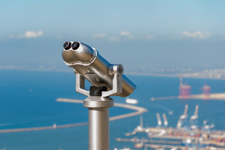 Close up of operated coin telescope is mounted on a sturdy base, pointing towards a distant scenic view in the park. The binoculars are mounted an observation point for tourists to view distant landscapesの写真素材