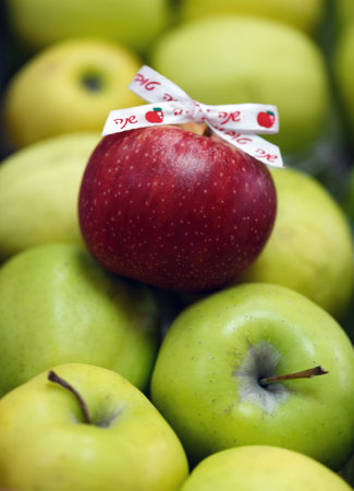 Group of green apples with one red apple in the center. Ribbon with the Hebrew inscription words shana tova is attached to it which means Happy New Year. Jewish holiday Rosh Hashanah Jerusalem, Israelの写真素材