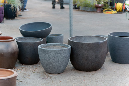 Collection of outdoor plant pots of varying sizes, colors and shapes. Most are gray and round with...