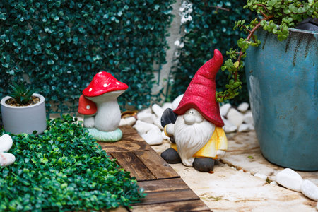 Garden gnome and mushroom decorations in a cozy outdoor. Whimsical scene features a gnome wearing a...