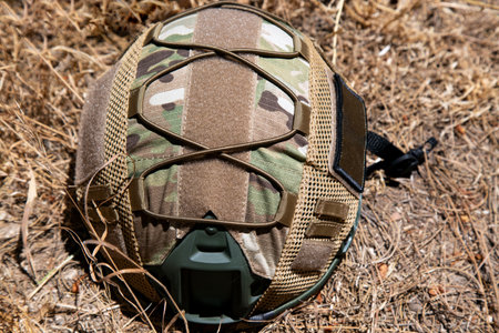 Us military tactical helmet in the sun. Photo isolated on a dry grass background. The concept of weapons for airsoft and urban protests. Airsoft war game equipment in daytime action. Military uniformの写真素材