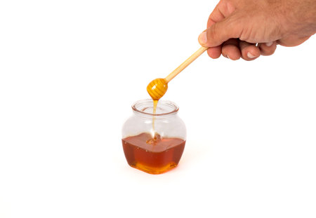 Rosh Hashanah, the Jewish New Year festival, showcases traditional symbols. A mans hand holding a...