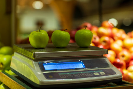 retro weight scale displaying ripe apples. Sharp focus on the scale and fruit textures, bokeh background. photo evoking tradition, prosperityの写真素材
