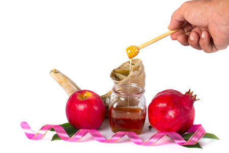 Rosh Hashanah, the Jewish New Year celebration, featuring traditional symbols. A man hand holding a honey dipper signifies sweetness for the year ahead. Designed with space textの写真素材