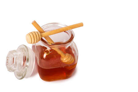 good isolated of Glass jar full of honey and wooden stick on a white background. Honey with wooden honey dipper. Close-up of Glass can full of honey and wooden stick on it. Clipping paths. Studio shotの写真素材