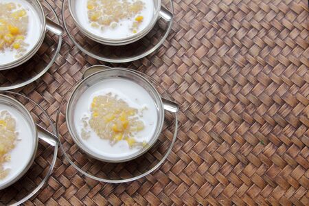 Thai dessert , sticky rice with coconut milk and corn on bambo weave tableの写真素材