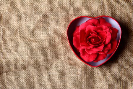 red rose in iron box shape heart form on crease burlap cloth . Lots of copy spaceの写真素材