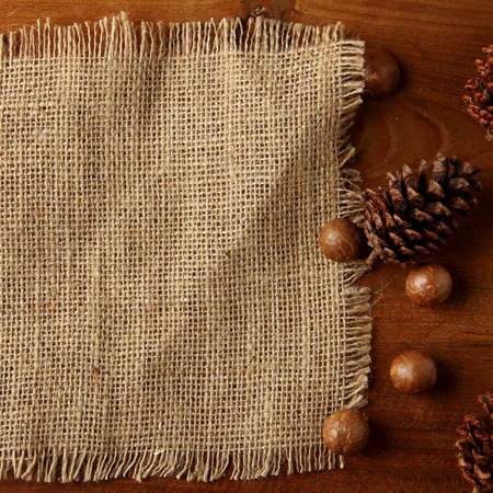 burlap on teakwood board  with cones araucaria almond nut with lot of copy space square formatの写真素材