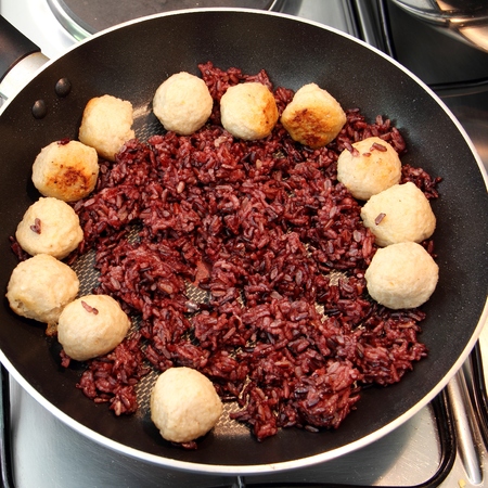 riceberry rice cooking wiht shrimp ball in the hot pan on stove  square format