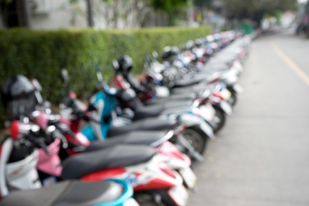 blur motor cycle parking on street near green tree wallの写真素材