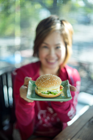 hamburger on  dish hold by  blur asia woman red shirtの写真素材