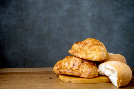 croissant bakery and half bun on teak wood table lighting and gray backgroundの写真素材