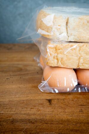 single sliced  bread and egg in plastic bag on wood teak