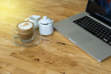 cup of hot chocolate and laptop computer for working on wood table