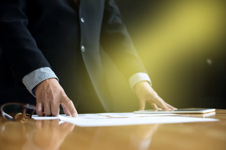 business man stand at the head of the table in boardroom black backgroundの写真素材