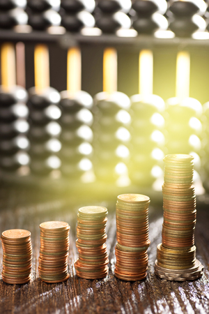 group of gold coin setting in graph form and abacus with studio Lightingの写真素材