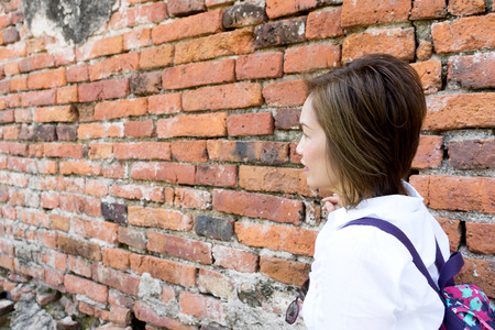 asian woman stand in front of old brick wallの写真素材