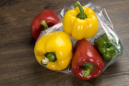 group of bell peppers in plastic bag on wood background
