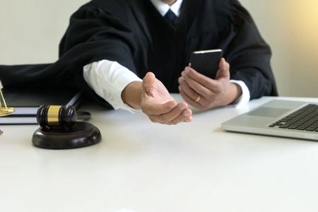 Judge use computer mobile phone in the office with Scales gavel hammer in office  give his help or ask bribe money for  corruptionの写真素材