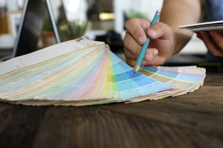 Graphic designer working with computer and color tone paper for choice the best color for the project on wood tableの写真素材
