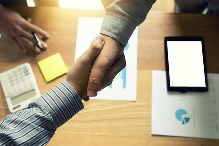executive businessman hand shake with another business man show their corporation tablet white screen with clipping path.の写真素材