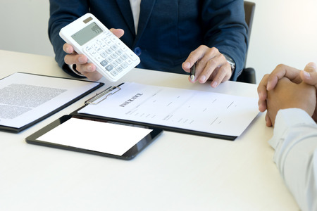Yound Business man insurance agent and customer look at the contract together at the table in office