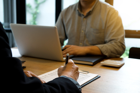Businessman and staff working with computer on wood table の写真素材
