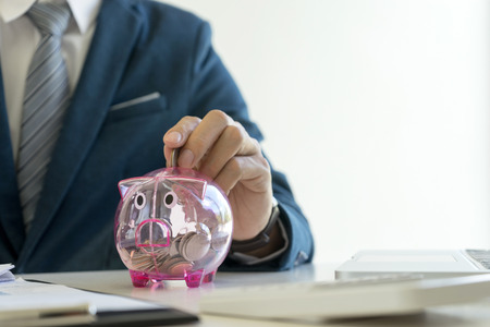 Business man hold collect coin in the row in front of the saving box concept economy investmentの写真素材