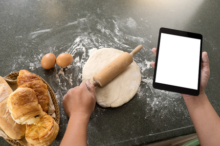in the kichen man or woman use tablet to learn and do Raw dough for bread  bake or cake from bakery raw material, white tablet screen with  clipping pathの写真素材