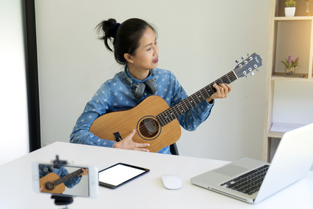 Young woman blogger with smartphone recording home video. beauty and technology music conceptの写真素材