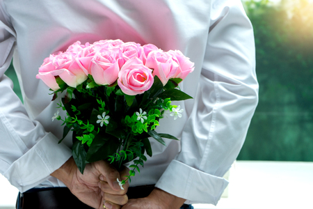 boy hide pink rose his back side for surprise gift to a girl lover concept valentine dayの写真素材