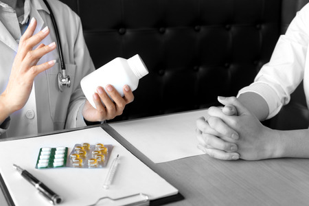 Doctor take care, Patient listening intently to a male doctor explaining patient symptoms or asking a question as they discuss paperwork together in a consultationの写真素材