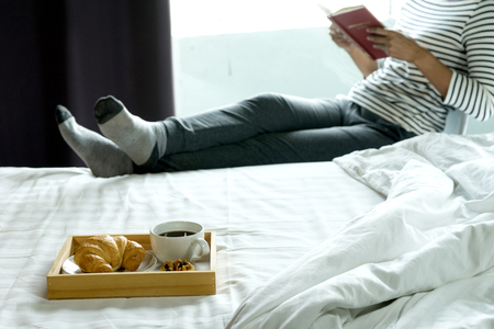 relax woman read a book on the bed for happy life day with her breakfastの写真素材