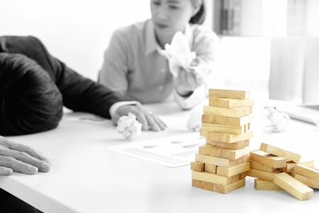 businessman and businesswoman sad wood blog depressed on the table , business problem not to work or failure. mix color with black and whiteの写真素材