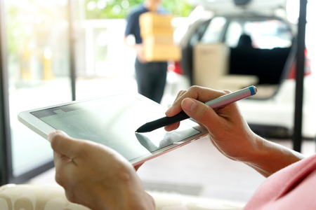 worker man delivery the boxs to woman home or office , with tablet for sign