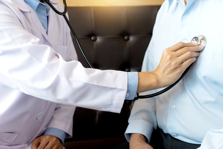 Doctor take care, Patient listening intently to a male doctor explaining patient symptoms or asking a question as they discuss paperwork together in a consultationの写真素材
