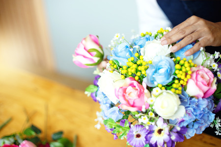 flower artist woman working to decorate  artificial flowers decorate on the table with many  color of paper and plastic flowerの写真素材