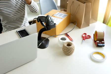 ecommerce concept, in office or home working prepare product in the box for send to customer who order by online. box for logistic with barcode scannerの写真素材