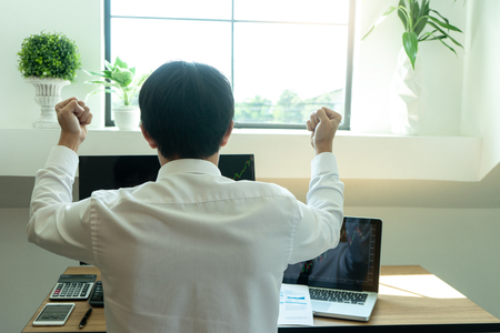 young businessman sit and look to the computer watch stock market. He excited when the stock market set index was the good point .の写真素材