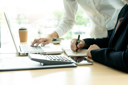Two businesswoman freelance worker work in the coffee shop ,on table have computer laptop and marketing paper graph chart with calculator.の写真素材