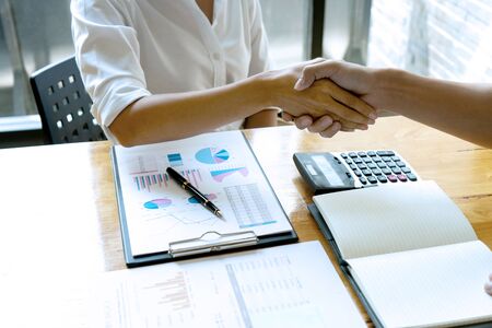 on the table business people hand shake with another business man woman on the table show their working about analysis marketing have graph chart on the tableの写真素材