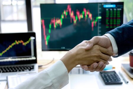 businessman shake hand at the office table between computer laptop , success or agreement about their job.の写真素材