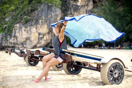 Woman sit on boat wheel and her hand hold scarf. The cloth fly wave by the windの写真素材