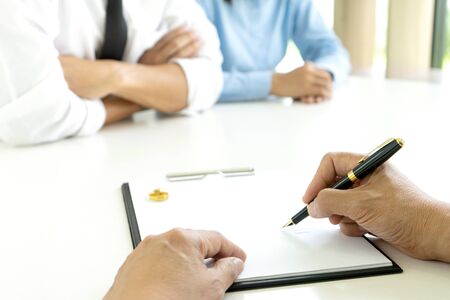 in the law office man and woman sit at the table to sign or not on the paper about marry or divorceの写真素材