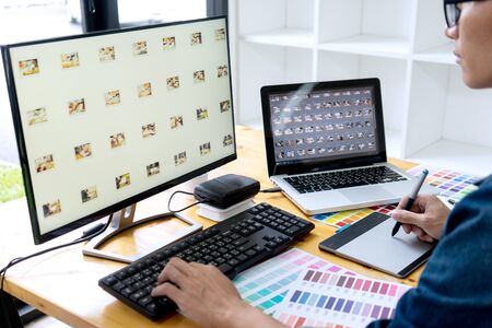 in the office  Businessman work and showing computer screen to coworker business woman with Color swatch samples on table in creative office.   Graphic designer conceptの写真素材