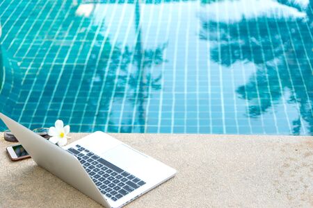 Laptop and smartphone near the swimming pool, modern businessman can work anywhere.の写真素材