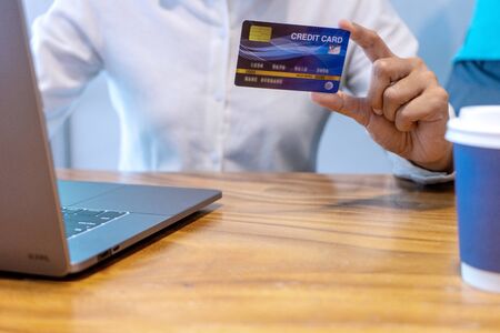 Young woman use credit card near the computer laptop and smartphone, on the wood desk table.の写真素材