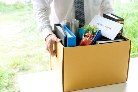 Young worker feel bad and sad, he receive resign note from his boss and company. Sad business man pack his belonging in the box and go back home.の写真素材