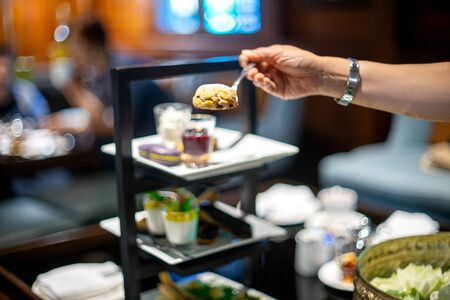 lady hand get food from high tea set on the table in restaurantの写真素材